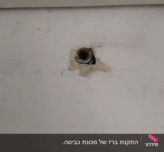 צינור מים חשוף בקיר עם סדקים מסביב